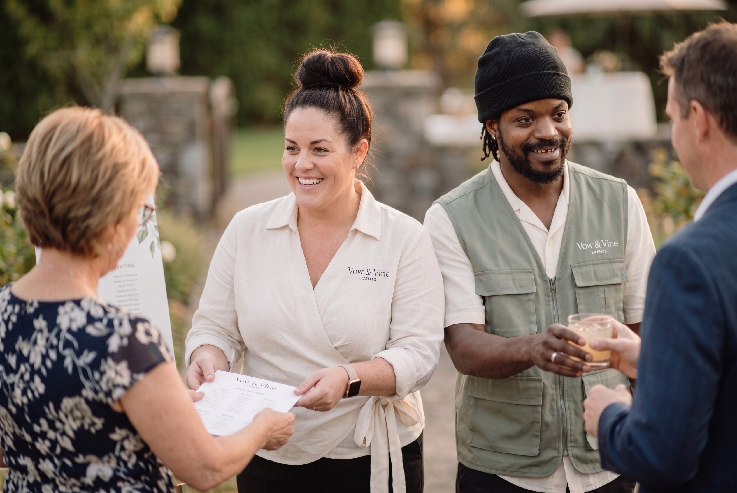 Vow & Vine staff greeting guests with the seating chart at an outdoor event
